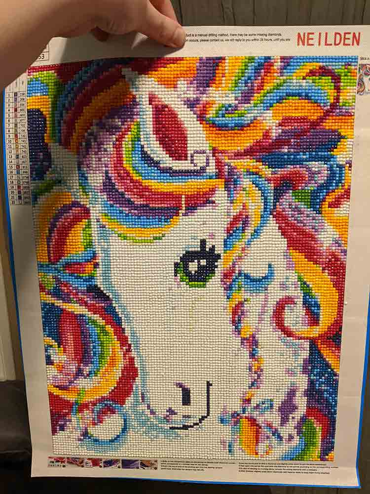 Hand holding a Lisa Frank style unicorn canvas.