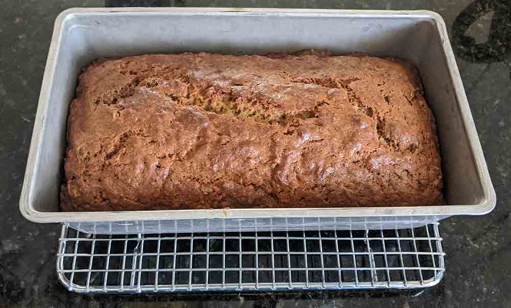 A single loaf of banana bread cooling on a small wire rack.