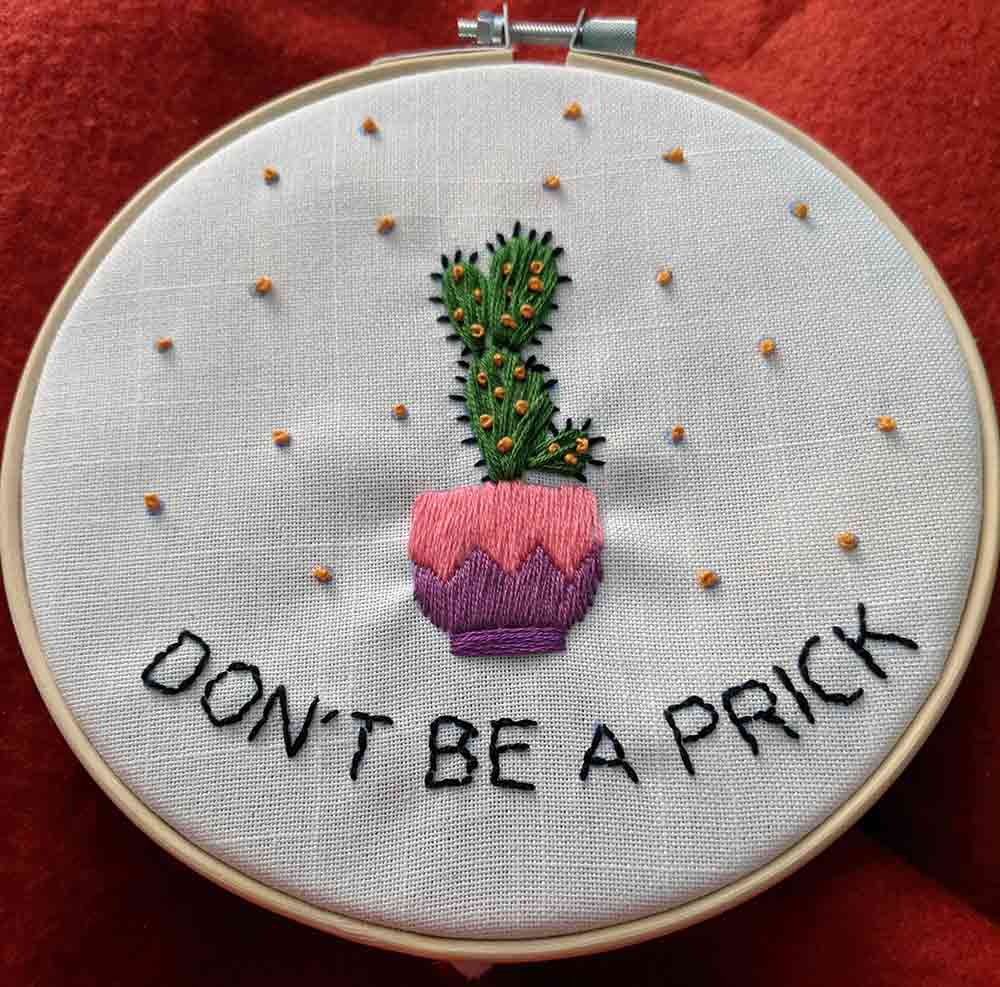 Embroidered cactus in a small pink and purple pot. Under the cactus is "Don't be a prick".