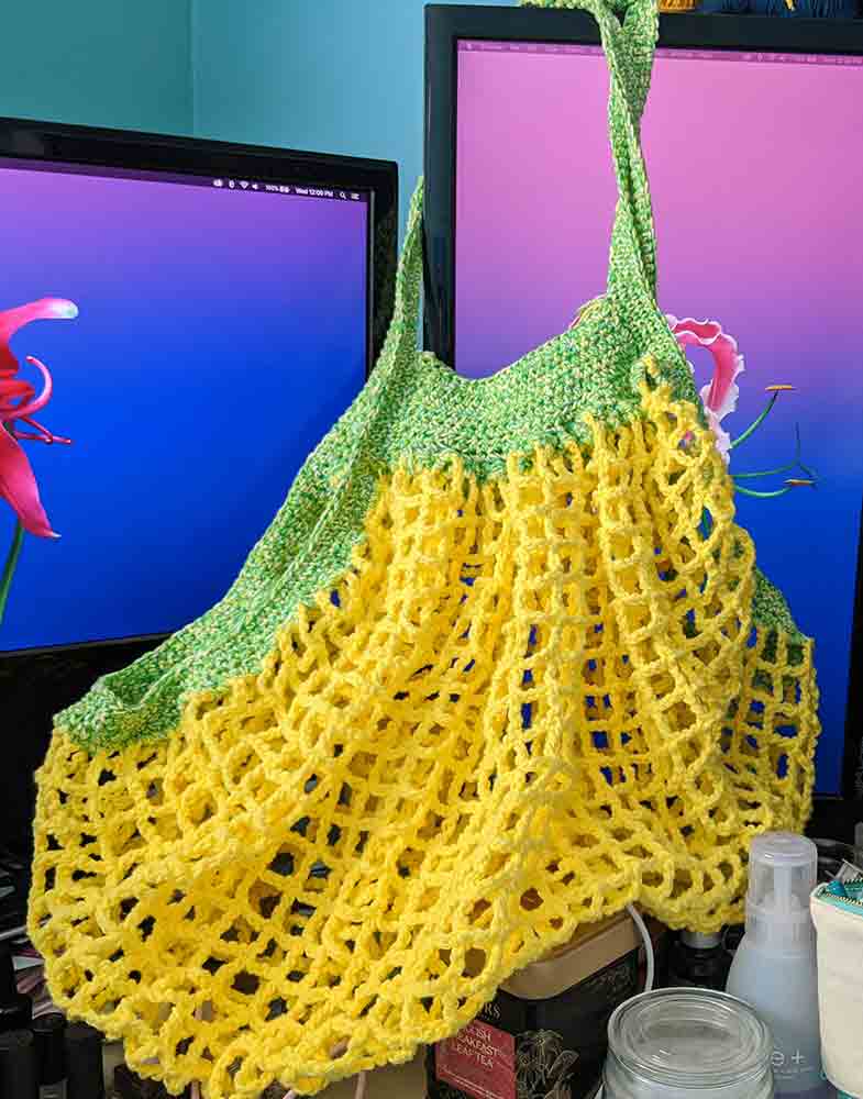 Yellow and green net market bag draped across computer monitors.