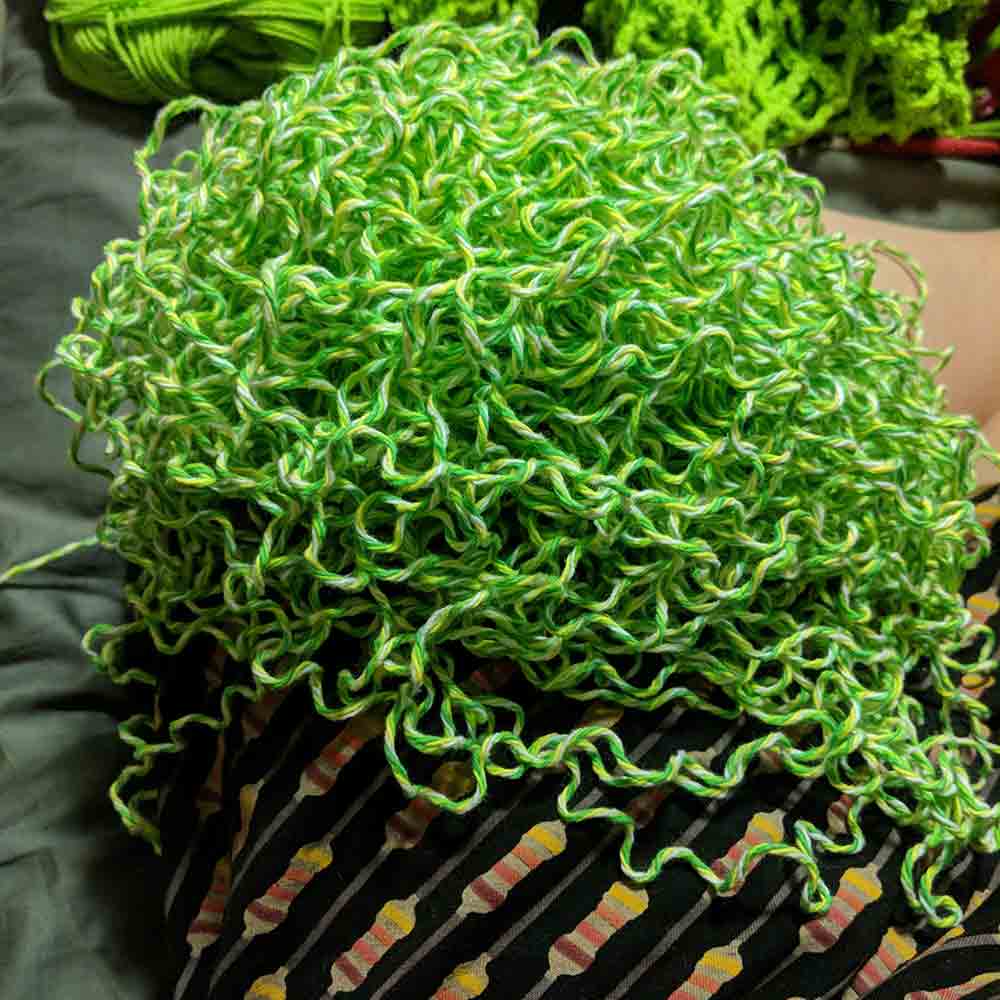 Tangled pile of green and yellow yarn lying on my knee.